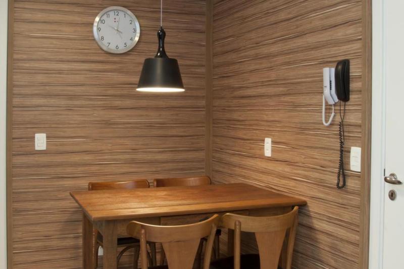Um dos pedidos do casal era que a cozinha, de 12,5 metros quadrados, tivesse uma copa. Para torná-la aconchegante, a opção foi cobrir duas paredes do recanto com painéis de acabamento melamínico marrom, que faz elegante composição com a mesa de madeira com quatro cadeiras e o restante do ambiente de cores neutras:imagem 3