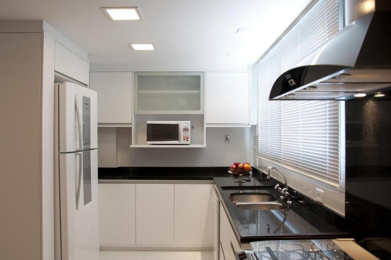 Do outro lado, a cozinha foi projetada com móveis de marcenaria com melamínico branco, granito preto e eletrodomésticos com acabamento em aço inox escovado:imagem 4