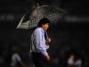 O técnico do San Martín, Víctor Riveira acompanha a partida sob a proteção do guarda-chuva
